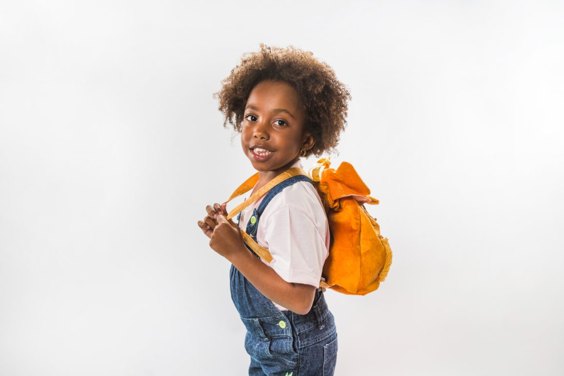 Élève souriante, cartable sur le dos, prête pour la rentrée
